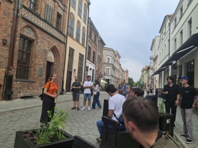 zdjęcia przedstawiają uczestników programu TSSP ExSci 2026 podczas zwiedzania Starówki Torunia z przewodnikiem oraz podczas wykładów naukowych. Kliknij, aby powiększyć zdjęcie.