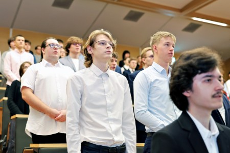 Kadry z inauguracji roku akademickiego w Audytorium Aleksandra Jabłońskiego - kolegium dziekańskie wraz z prorektorką za stołem oraz studenci i nauczyciele oraz administracja siedzący na sali. Kliknij, aby powiększyć zdjęcie.