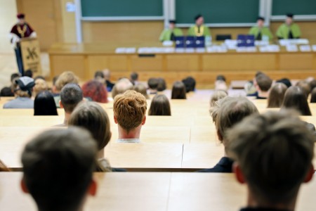 Kadry z inauguracji roku akademickiego w Audytorium Aleksandra Jabłońskiego - kolegium dziekańskie wraz z prorektorką za stołem oraz studenci i nauczyciele oraz administracja siedzący na sali. Kliknij, aby powiększyć zdjęcie.