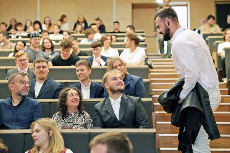 Kadry z inauguracji roku akademickiego w Audytorium Aleksandra Jabłońskiego - kolegium dziekańskie wraz z prorektorką za stołem oraz studenci i nauczyciele oraz administracja siedzący na sali. Kliknij, aby powiększyć zdjęcie.