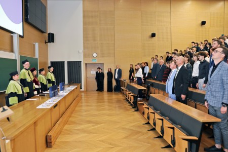 Kadry z inauguracji roku akademickiego w Audytorium Aleksandra Jabłońskiego - kolegium dziekańskie wraz z prorektorką za stołem oraz studenci i nauczyciele oraz administracja siedzący na sali. Kliknij, aby powiększyć zdjęcie.