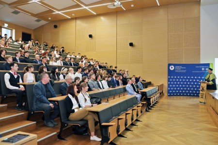 Kadry z inauguracji roku akademickiego w Audytorium Aleksandra Jabłońskiego - kolegium dziekańskie wraz z prorektorką za stołem oraz studenci i nauczyciele oraz administracja siedzący na sali. Kliknij, aby powiększyć zdjęcie.
