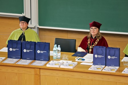 Kadry z inauguracji roku akademickiego w Audytorium Aleksandra Jabłońskiego - kolegium dziekańskie wraz z prorektorką za stołem oraz studenci i nauczyciele oraz administracja siedzący na sali. Kliknij, aby powiększyć zdjęcie.