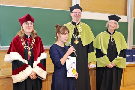 Kadry z inauguracji roku akademickiego w Audytorium Aleksandra Jabłońskiego - kolegium dziekańskie wraz z prorektorką za stołem oraz studenci i nauczyciele oraz administracja siedzący na sali. Kliknij, aby powiększyć zdjęcie.