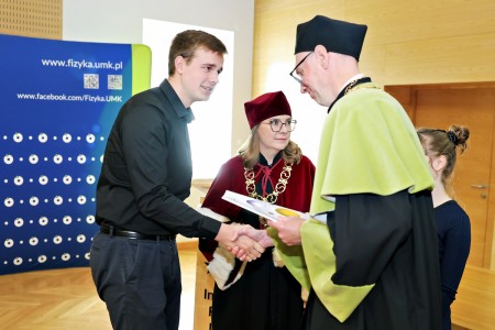Kadry z inauguracji roku akademickiego w Audytorium Aleksandra Jabłońskiego - kolegium dziekańskie wraz z prorektorką za stołem oraz studenci i nauczyciele oraz administracja siedzący na sali. Kliknij, aby powiększyć zdjęcie.