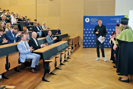 Kadry z inauguracji roku akademickiego w Audytorium Aleksandra Jabłońskiego - kolegium dziekańskie wraz z prorektorką za stołem oraz studenci i nauczyciele oraz administracja siedzący na sali. Kliknij, aby powiększyć zdjęcie.