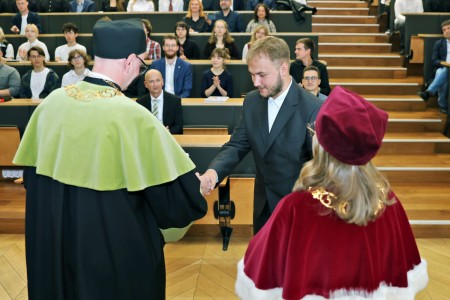 Kadry z inauguracji roku akademickiego w Audytorium Aleksandra Jabłońskiego - kolegium dziekańskie wraz z prorektorką za stołem oraz studenci i nauczyciele oraz administracja siedzący na sali. Kliknij, aby powiększyć zdjęcie.