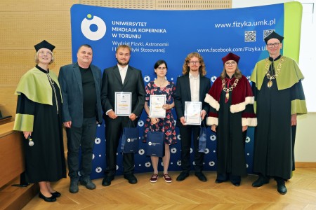 Kadry z inauguracji roku akademickiego w Audytorium Aleksandra Jabłońskiego - kolegium dziekańskie wraz z prorektorką za stołem oraz studenci i nauczyciele oraz administracja siedzący na sali. Kliknij, aby powiększyć zdjęcie.