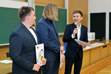 Kadry z inauguracji roku akademickiego w Audytorium Aleksandra Jabłońskiego - kolegium dziekańskie wraz z prorektorką za stołem oraz studenci i nauczyciele oraz administracja siedzący na sali. Kliknij, aby powiększyć zdjęcie.