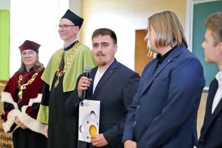 Kadry z inauguracji roku akademickiego w Audytorium Aleksandra Jabłońskiego - kolegium dziekańskie wraz z prorektorką za stołem oraz studenci i nauczyciele oraz administracja siedzący na sali. Kliknij, aby powiększyć zdjęcie.