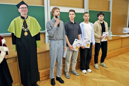 Kadry z inauguracji roku akademickiego w Audytorium Aleksandra Jabłońskiego - kolegium dziekańskie wraz z prorektorką za stołem oraz studenci i nauczyciele oraz administracja siedzący na sali. Kliknij, aby powiększyć zdjęcie.