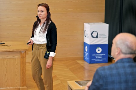 Kadry z inauguracji roku akademickiego w Audytorium Aleksandra Jabłońskiego - kolegium dziekańskie wraz z prorektorką za stołem oraz studenci i nauczyciele oraz administracja siedzący na sali. Kliknij, aby powiększyć zdjęcie.