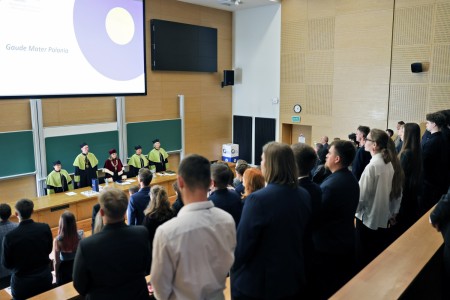 Kadry z inauguracji roku akademickiego w Audytorium Aleksandra Jabłońskiego - kolegium dziekańskie wraz z prorektorką za stołem oraz studenci i nauczyciele oraz administracja siedzący na sali. Kliknij, aby powiększyć zdjęcie.
