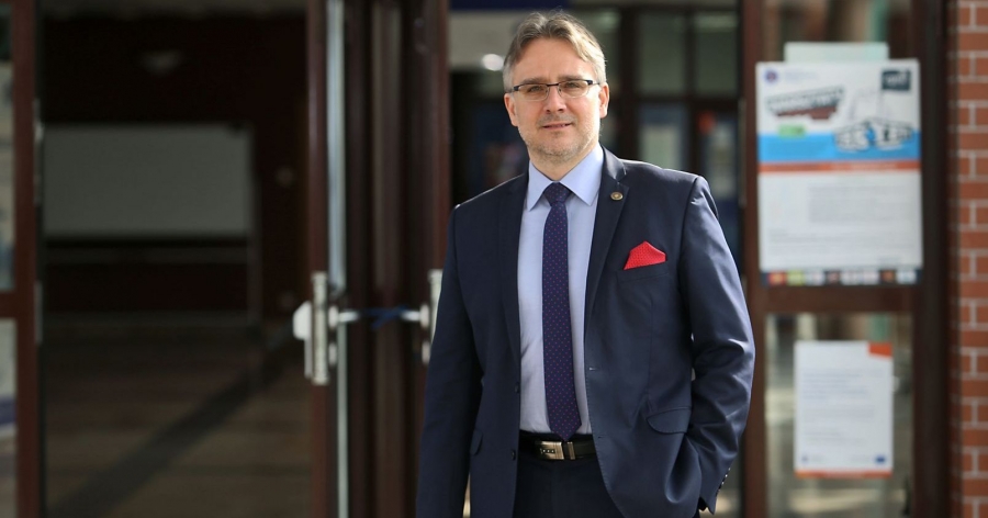 Prof. dr. hab. Maciej Zastempowski stoi przed wejściem na Wydział Nauk Ekonomicznych i Zarządzania UMK