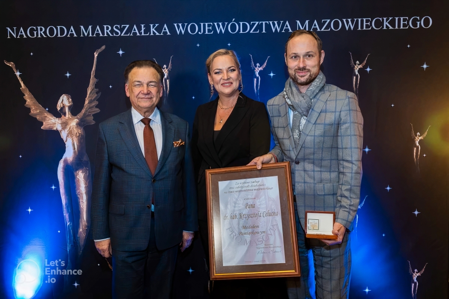 Trójka ludzi - dwóch mężczyzn i jedna kobieta w odświętnych ubraniach. Jeden trzyma ramkę z gratulacjami. 