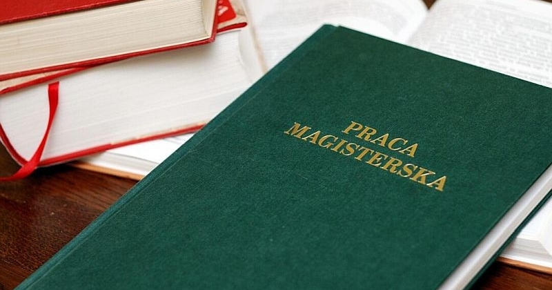 Na pierwszym planie praca dyplomowa w zielonej oprawie z napisem 