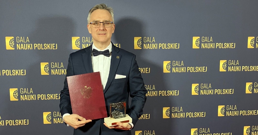 Prof. Zastempowski pozuje na ściance z napisem 