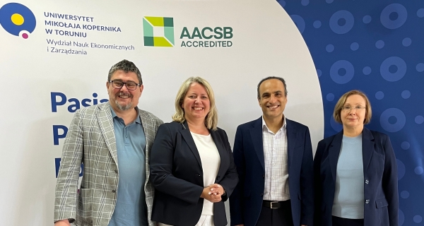 4 professors standing on the background with faculty and aacsb logos.