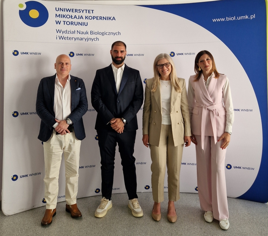 Umberto Grande with his supervisors standing and smiling in front of the Faculty of Biological and Veterinary Sciences of Nicolaus Copernicus University backdrop 