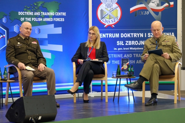 Two men in military uniforms, one women in civil clothing siting on a stage.
