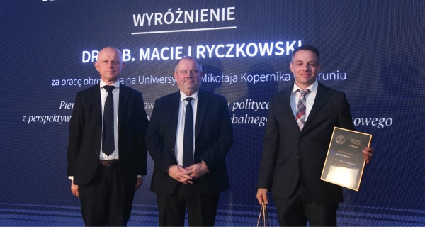 Two men and dr hab. MAciej Ryczkowski receiving the reward.