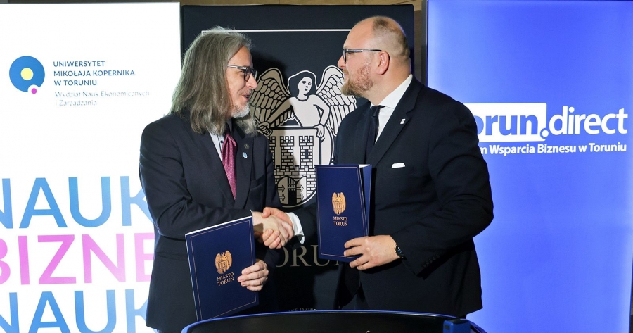 Dr hab. Adam Kola, prof. UMK i prezydent Torunia PawełGulewski ściskają sobie dłonie w drugich trzymając teczki z podpisanym listem intencyjnym