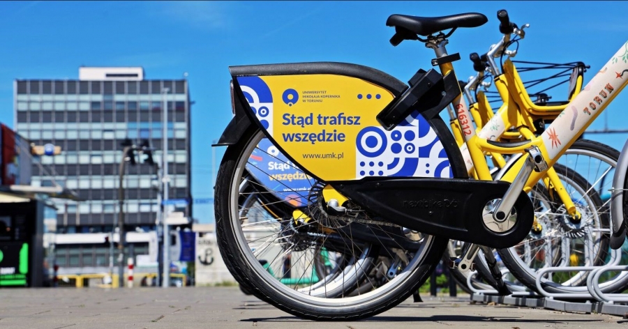 A city bike featuring artwork promoting Nicolaus Copernicus University against the backdrop of the Rector?s Office