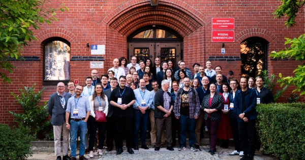 Uczestnicy i uczestniczki seminarium profesora Adama Izdebskiego stojący przy wejściu do Collegium Maius UMK
