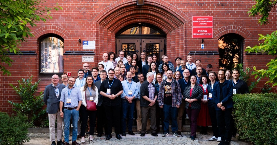 Uczestnicy i uczestniczki seminarium profesora Adama Izdebskiego stojący przy wejściu do Collegium Maius UMK