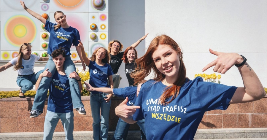 Kilkoro studentów w koszulkach z napism UMK stąd trafisz wszędzie , w tle aula umk