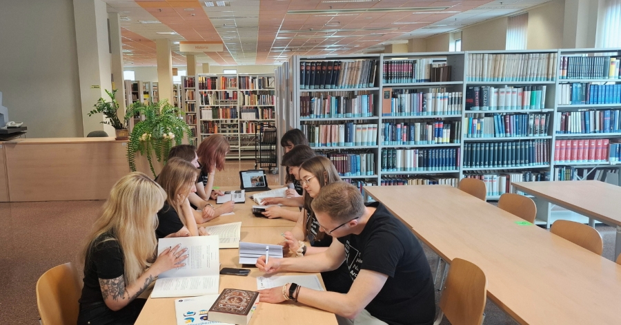 Grupa studentów uczących się przy stoliku w bibliotece.