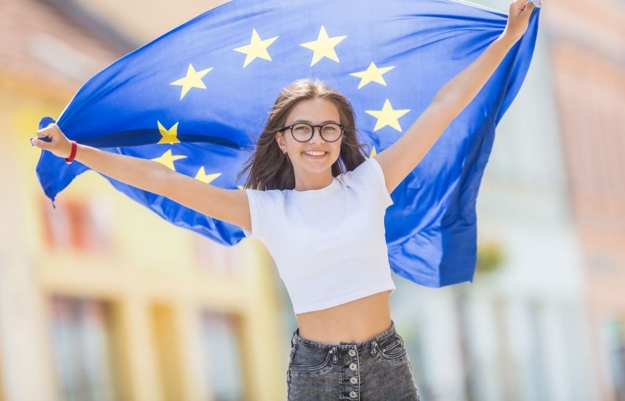 Młoda uśmiechnięta dziewczyna z rozpostartą flagą unijną